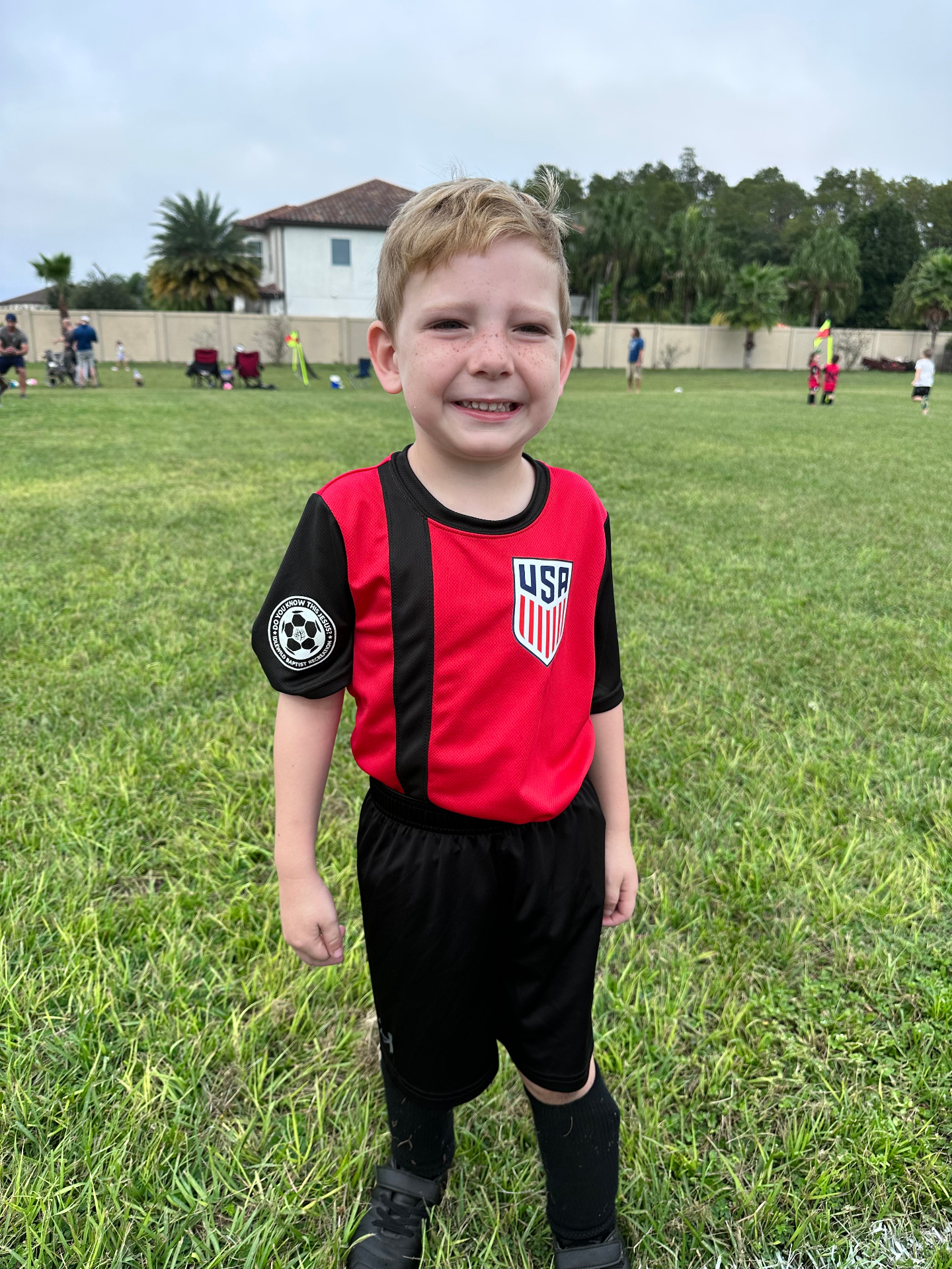 Youth soccer player smiling on the Idlewild field in a red jersey